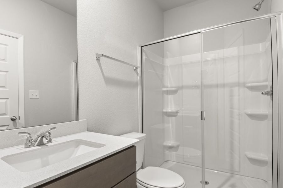 Image of a primary bathroom with a white vanity and large mirror, and a white vinyl walk-in shower