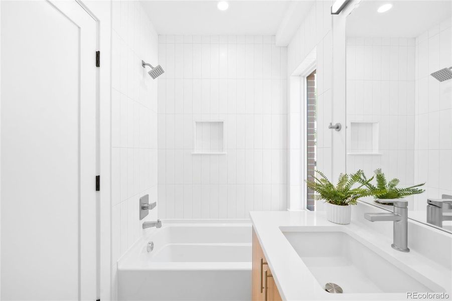 A large window brightens this modern full bath, where sleek tile and polished fixtures create a spa-like feel.