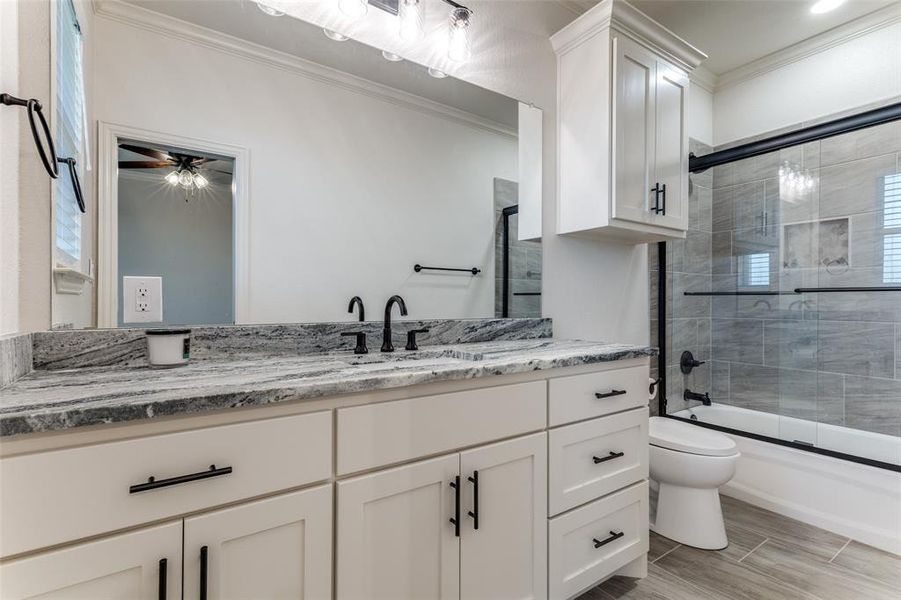 Bathroom featuring crown molding, vanity, and enclosed tub / shower combo