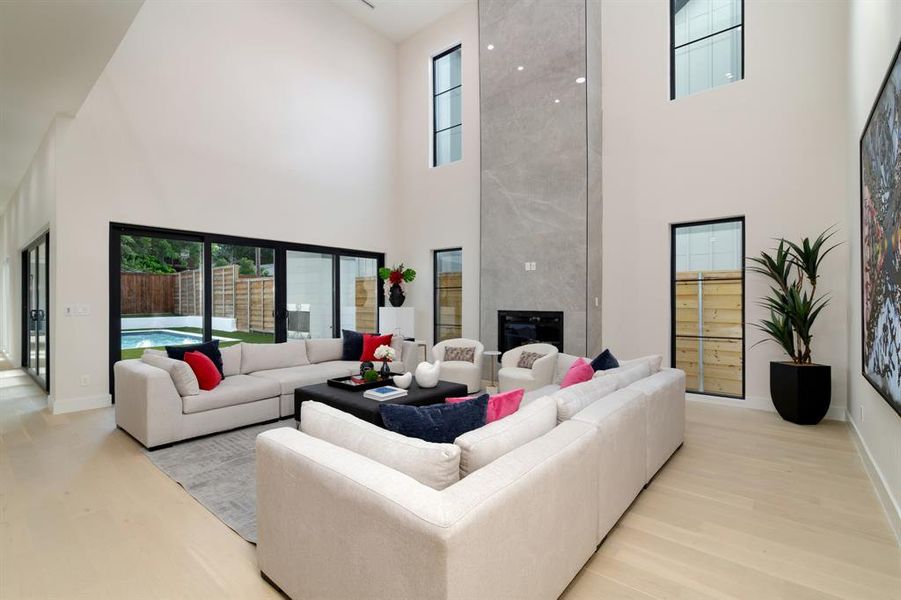 Living room featuring a high ceiling, light hardwood / wood-style floors, and a fireplace