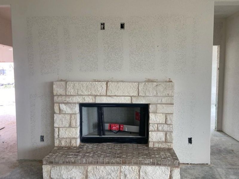 Fireplace featuring a light-toned stone surround, a black firebox, and a tiled hearth