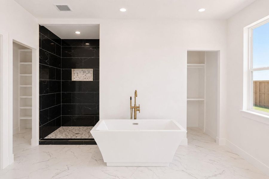 Indulge in a primary bathroom retreat, boasting a freestanding soaking tub and a spacious walk-in shower.
