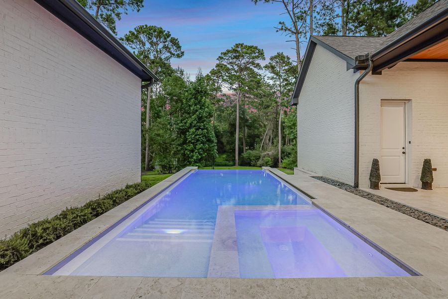 Resort-inspired pool and spa create a true backyard retreat, featuring clean modern lines, a tanning ledge, and a relaxing spa illuminated for stunning evening ambiance. Surrounded by elegant stone decking and framed by a private wooded backdrop with no rear neighbors, this outdoor oasis offers exceptional privacy and tranquility. Whether enjoying a refreshing swim, soaking in the spa, or entertaining guests on the expansive patio, this space delivers the perfect blend of luxury, comfort, and indoor-outdoor