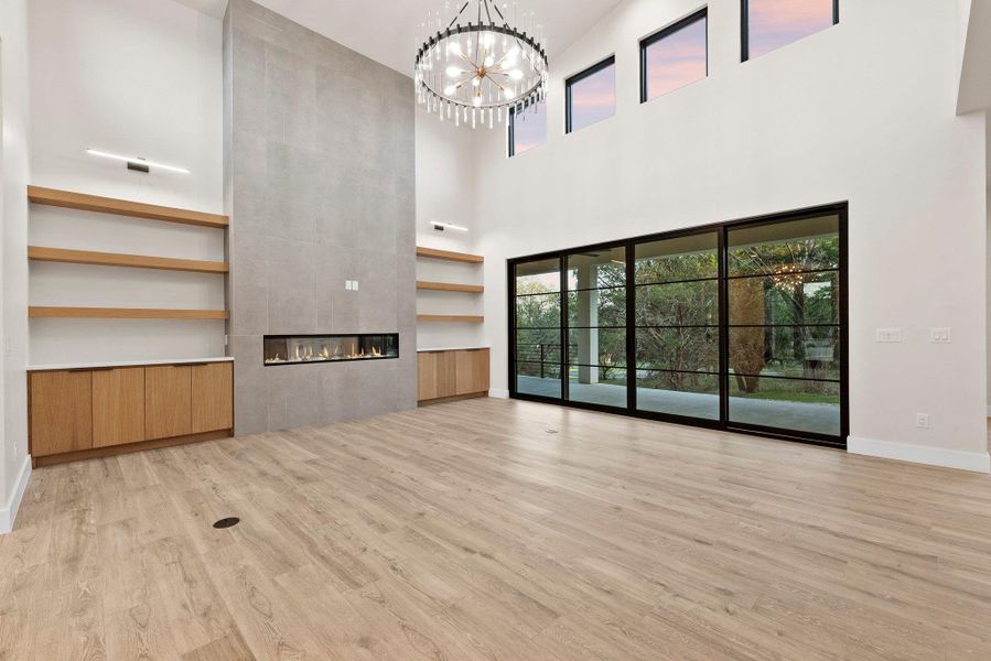A grand living space with towering ceilings and a contemporary fireplace provides serene views through expansive glass doors.