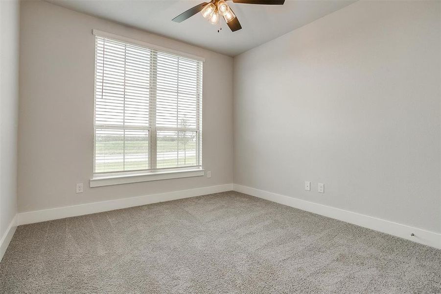 Carpeted spare room featuring ceiling fan and a healthy amount of sunlight