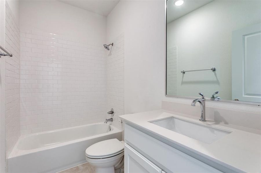 Full bathroom with toilet, tiled shower / bath combo, and vanity