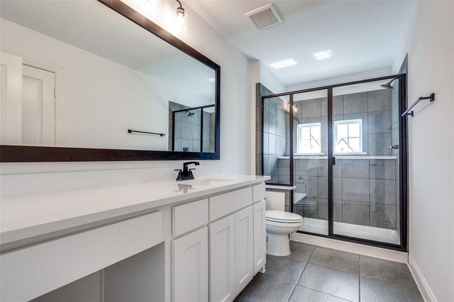 Bathroom featuring walk in shower, vanity, toilet, and tile floors