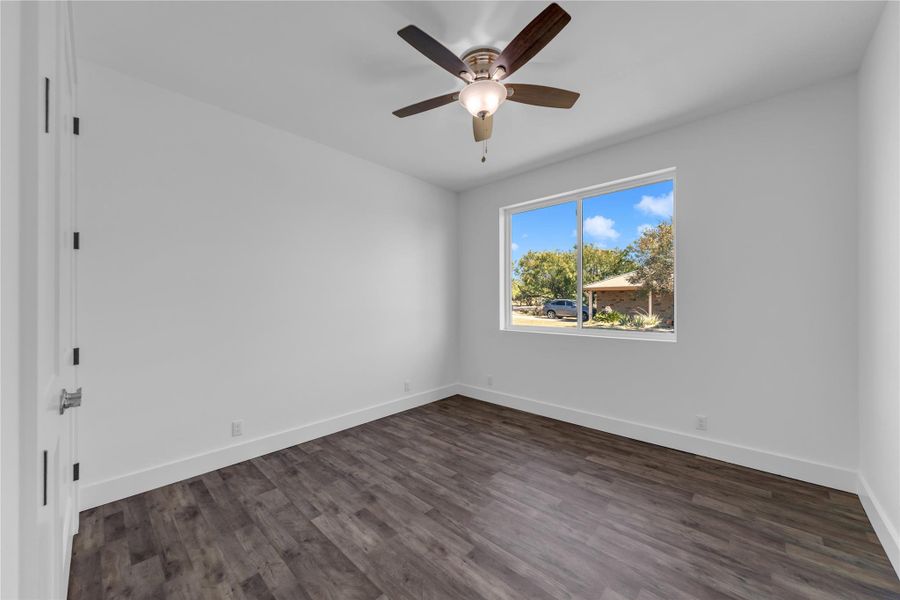 Guest Bedroom 1; Rich wood-look flooring and a wide window create a comfortable, inviting secondary bedroom space.