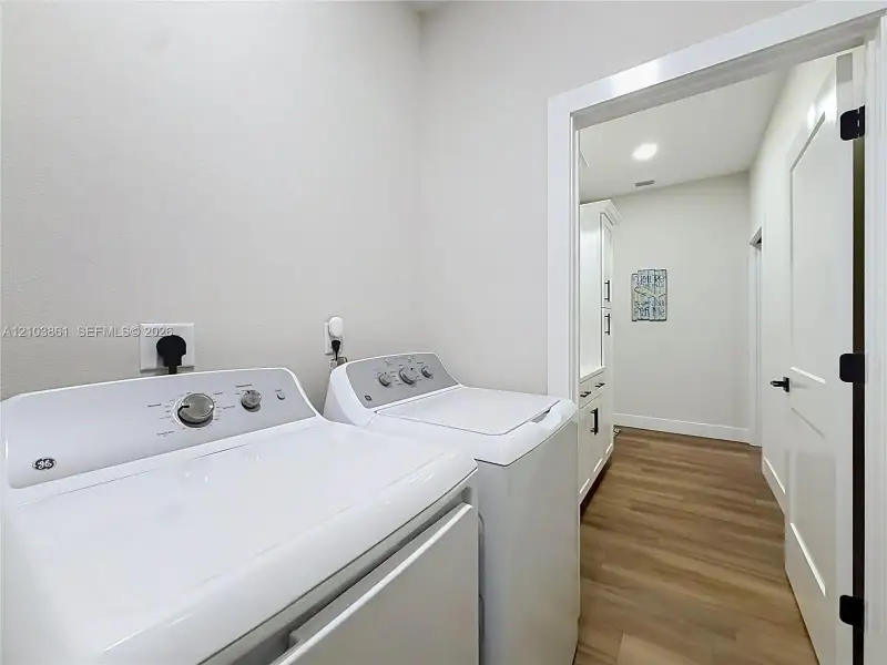 Laundry room featuring wood-finish flooring, white cabinetry, and recessed lighting