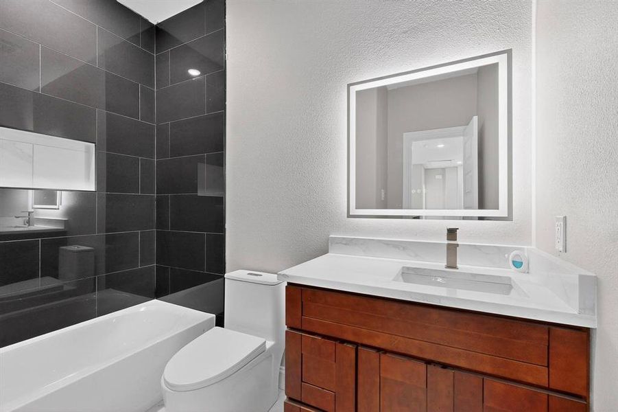 Bathroom with vanity, a textured wall, and shower / washtub combination