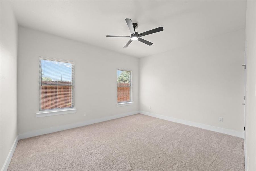 Spacious room featuring neutral carpeting, light-toned walls, and a modern ceiling fan with integrated lighting Spacious room featuring neutral carpeting, light-toned walls, and a modern ceiling fan with integrated lighting