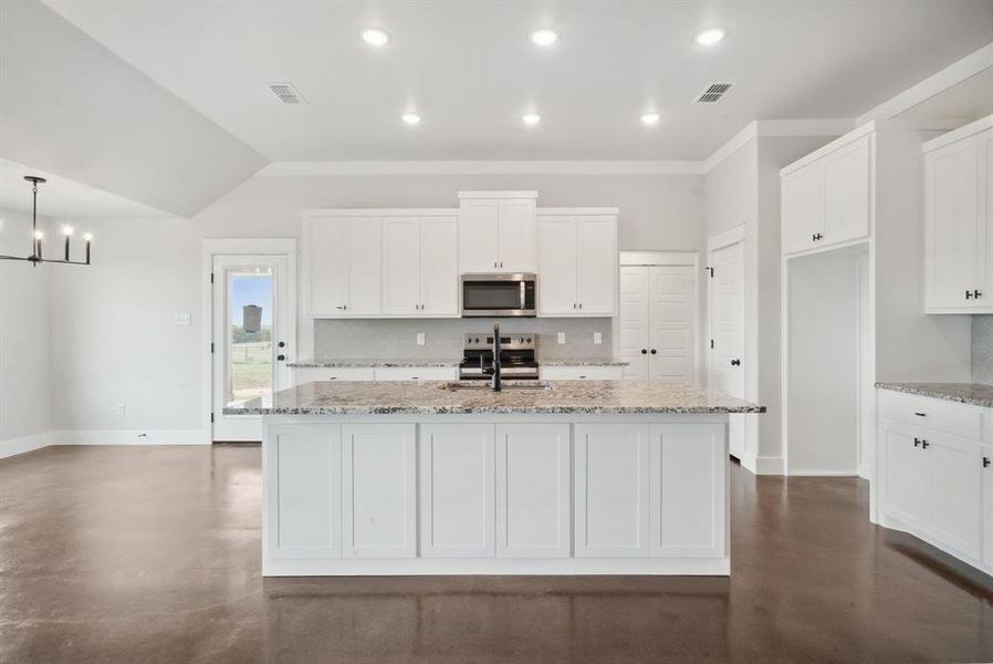 Kitchen featuring appliances with stainless steel finishes, white cabinetry, decorative backsplash, and light stone counters