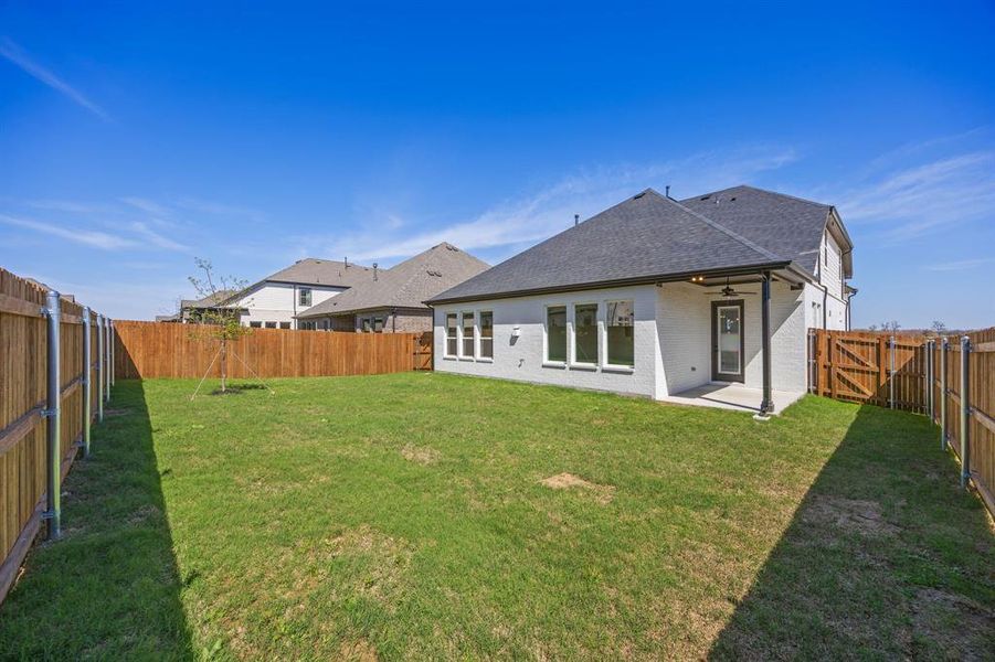 Rear view of property with a fenced backyard, a patio area, a gate, roof with shingles, and brick siding