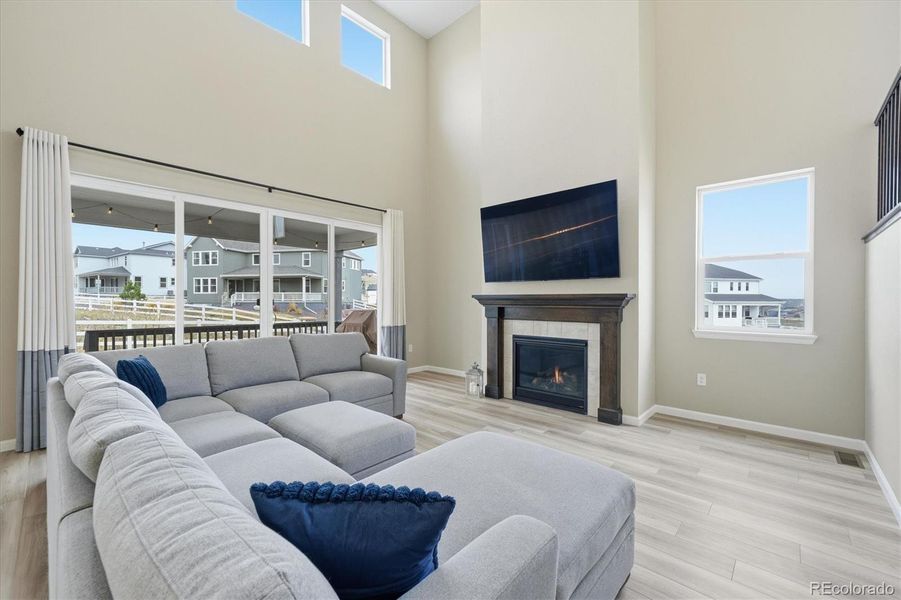 Living room with soaring ceilings, a gas fireplace, and the upgraded, large, center-opening sliding doors for added natural light and extra air flow.