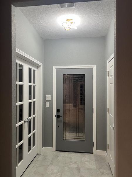 Doorway to outside with a textured ceiling and french doors Doorway to outside with a textured ceiling and french doors