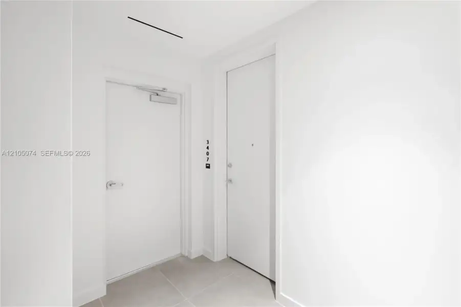 Entryway featuring solid-core doors, neutral large-format tile flooring, and integrated door hardware