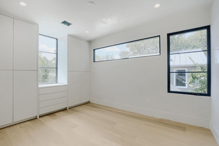 Blonde hardwood floors complement built-in storage and large windows in this bright room.