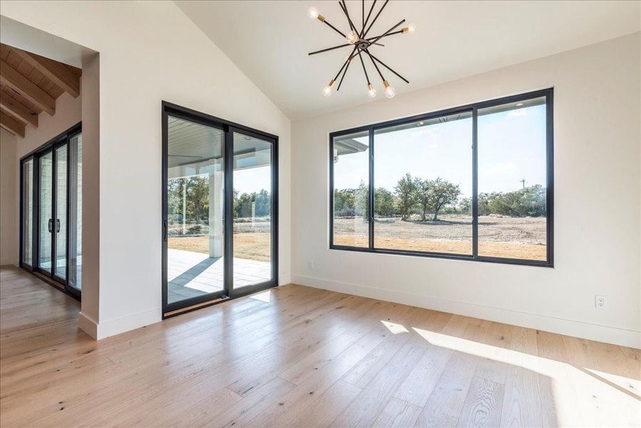 The charming daily dining area, highlighted by a beautiful chandelier, offers views of the stunning acreage and outdoor covered patio. Relax and savor your meals in this peaceful setting.