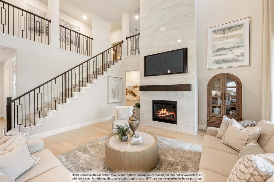 Two-story living room with stone fireplace, open staircase, and hardwood floors