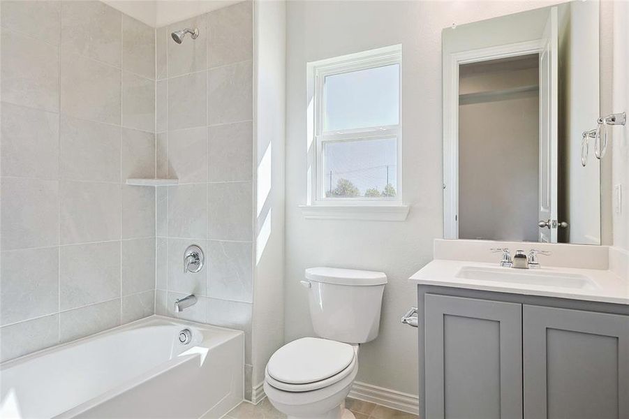 Full bathroom featuring tile patterned floors, tiled shower / bath combo, vanity, and toilet