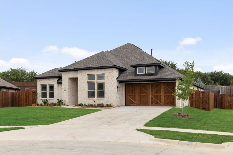 Single-story home with light brick exterior, wood garage doors, and manicured front lawn Single-story home with light brick exterior, wood garage doors, and manicured front lawn