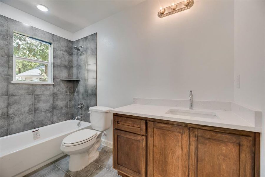 Full bathroom featuring tile patterned flooring, toilet, tiled shower / bath, and vanity