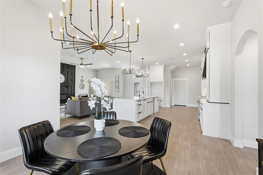 Dining area with light wood finished floors, a chandelier, a ceiling fan, and recessed lighting