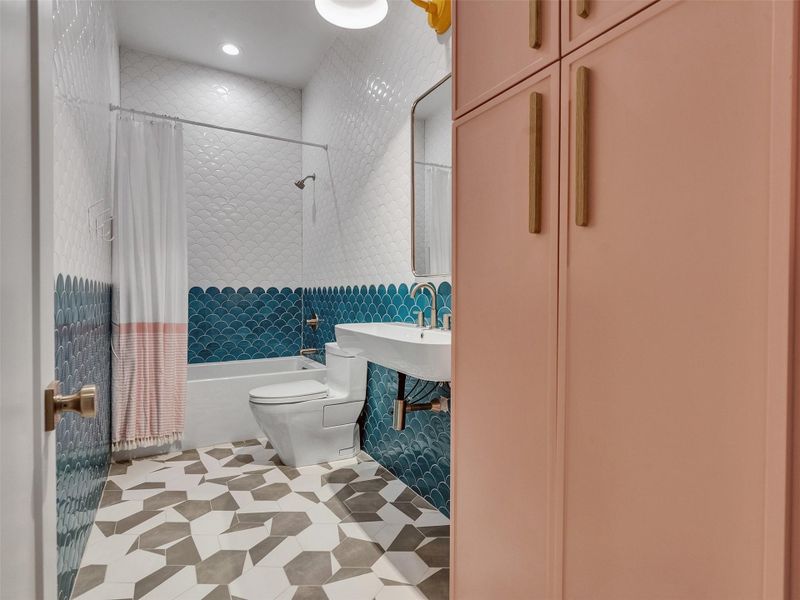Every detail of this guest bathroom invites relaxation and joy. The mermaid-scale tile design adds a playful nod to ocean life, while the tub and shower combo and stylish vanity make it as functional as it is beautiful. Guests can rinse off after a beach day, soak away the salt air, or simply enjoy the calm, cheerful vibe that mirrors the rhythm of island living. It’s a space that makes everyone feel instantly at home in Galveston. Every detail of this guest bathroom invites relaxation and joy. The mermaid-scale tile design adds a playful nod to ocean life, while the tub and shower combo and stylish vanity make it as functional as it is beautiful. Guests can rinse off after a beach day, soak away the salt air, or simply enjoy the calm, cheerful vibe that mirrors the rhythm of island living. It’s a space that makes everyone feel instantly at home in Galveston.