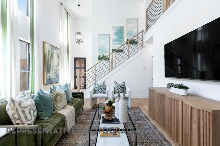 Living area with stairs, a high ceiling, light wood-type flooring, a chandelier, and baseboards Living area with stairs, a high ceiling, light wood-type flooring, a chandelier, and baseboards