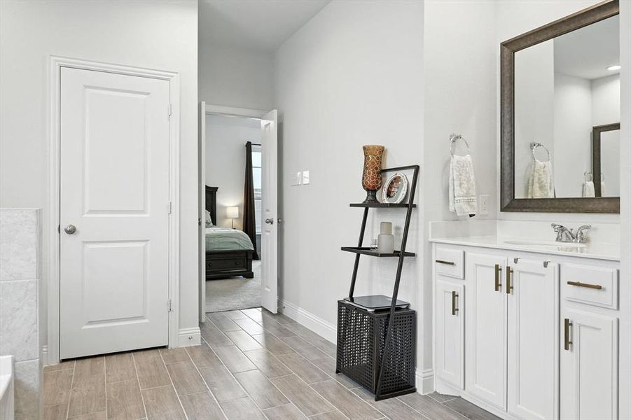 Full bath with vanity, wood finish floors, ensuite bathroom, and a bathtub