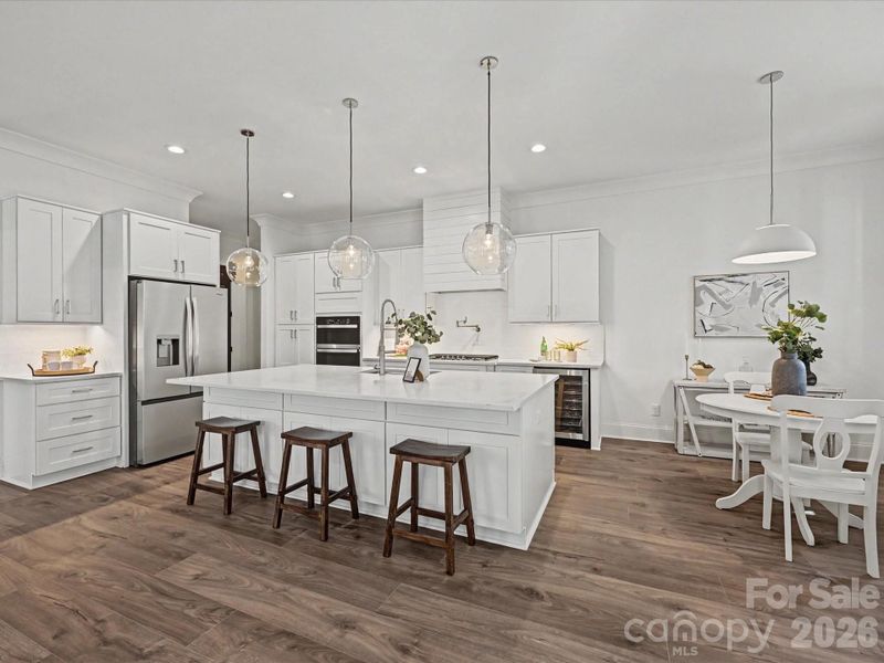 Stunning chef’s kitchen featuring a large center island, quartz countertops, stainless steel appliances, custom cabinetry, and modern pendant lighting—perfect for cooking and entertaining.