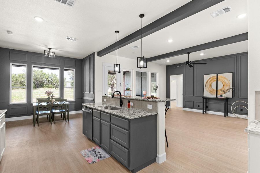 Kitchen featuring a decorative wall, light stone counters, gray cabinets, pendant lighting, and light wood-style flooring