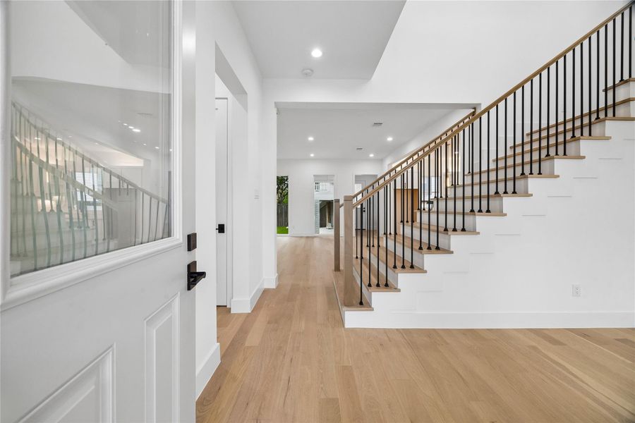 The entry sequence introduces the home’s contemporary architectural approach through engineered wood flooring, modern stair detailing, clean-lined finishes, and long interior sightlines extending into the main living areas. Natural light carries through the front of the home while the scale and openness of the layout create an immediate sense of flow upon arrival.