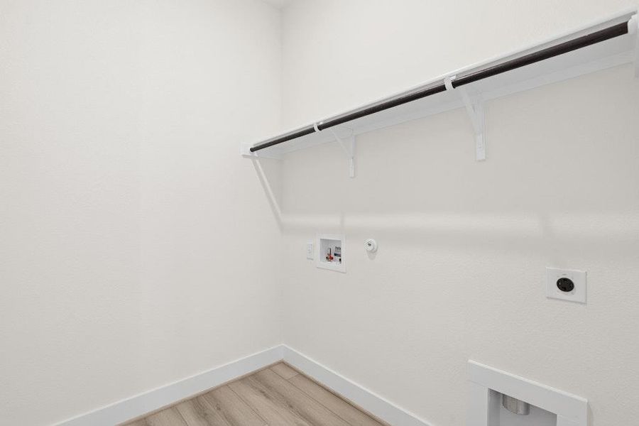 Laundry room featuring hookup for a gas dryer, hookup for an electric dryer, hookup for a washing machine, and light wood-style floors Laundry room featuring hookup for a gas dryer, hookup for an electric dryer, hookup for a washing machine, and light wood-style floors