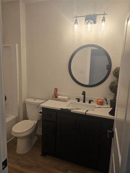 Bathroom featuring vanity, shower / tub combination, and dark wood-style flooring