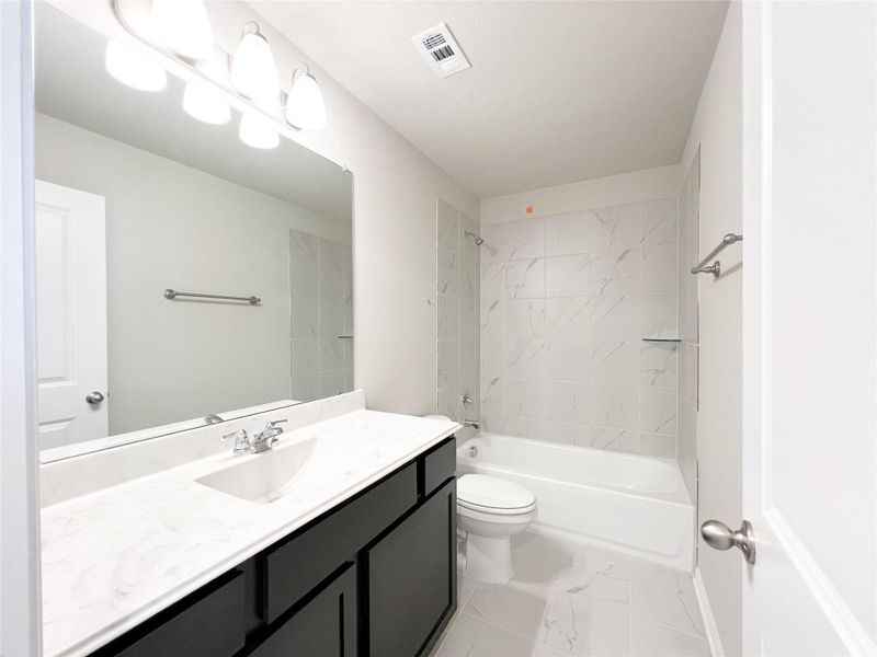 Bathroom with visible vents, marble finish floor, toilet, vanity, and shower / bathing tub combination Bathroom with visible vents, marble finish floor, toilet, vanity, and shower / bathing tub combination
