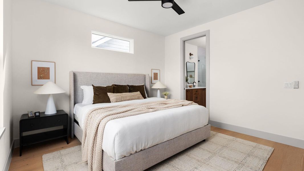 Bedroom with light wood-style floors, a ceiling fan, and connected bathroom