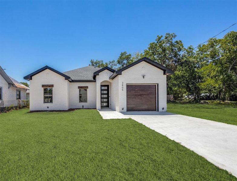 View of front of property with a front yard and a garage