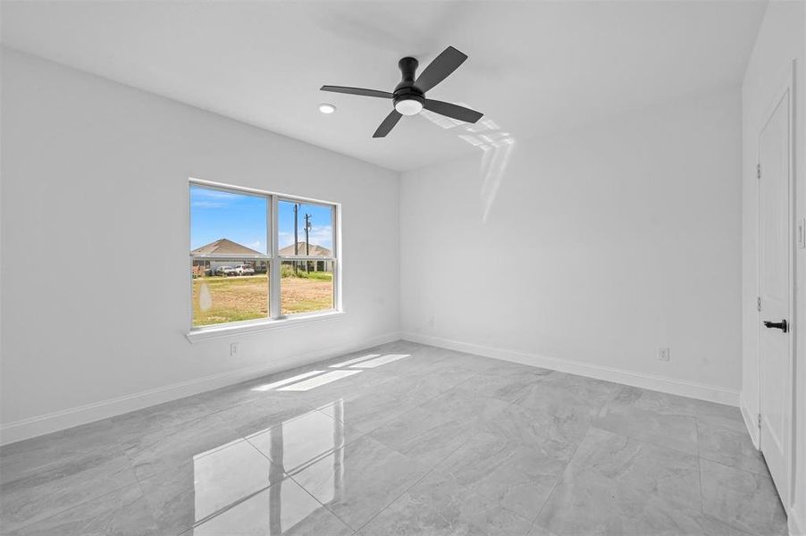 Tiled spare room featuring ceiling fan