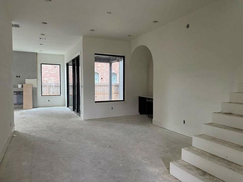 Dining Area- Open-concept living and dining with soaring ceilings, elegant arched architectural detail, and oversized black-framed windows. Flooring and finishes in progress. (Construction Photo as of 3/8/26 - Edited)