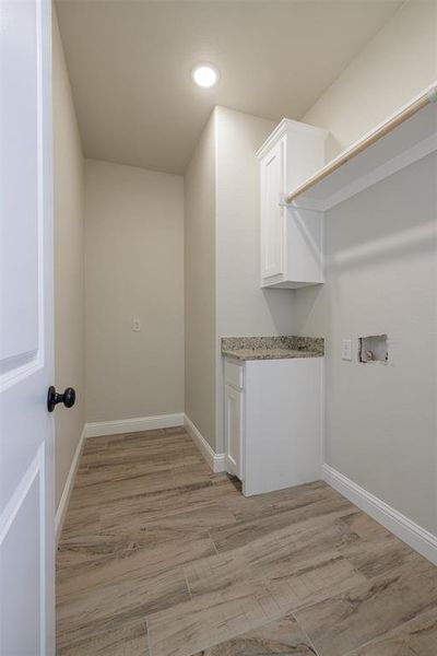 Laundry room featuring light hardwood / wood-style flooring, washer hookup, and cabinets