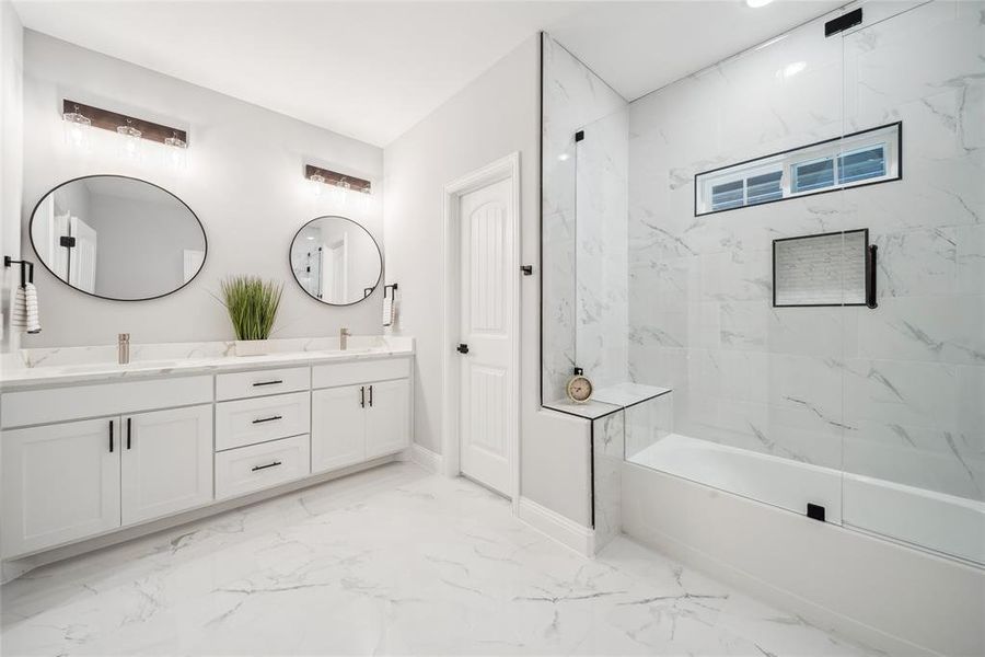 Contemporary bathroom featuring a double vanity with white cabinetry, matte black hardware, and two round mirrors