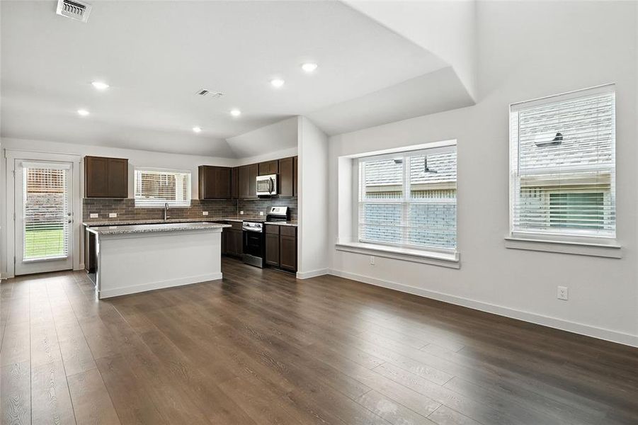 Kitchen with dark brown cabinets, appliances with stainless steel finishes, plenty of natural light, dark wood finished floors, and recessed lighting Kitchen with dark brown cabinets, appliances with stainless steel finishes, plenty of natural light, dark wood finished floors, and recessed lighting