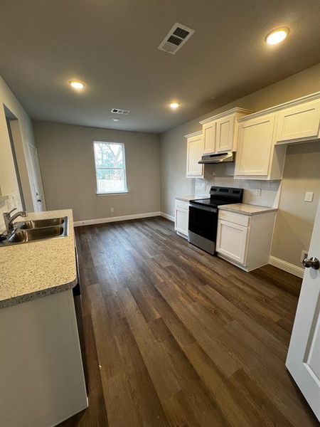 Kitchen with dark hardwood / wood-style floors, ventilation hood, white cabinetry, sink, and stove