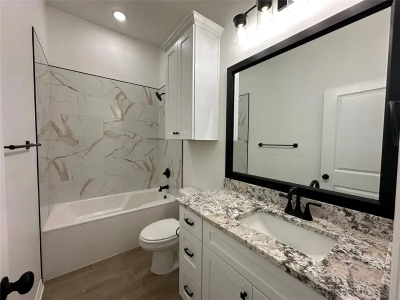 Bathroom featuring a white vanity with a granite countertop, integrated sink, and matte black faucet