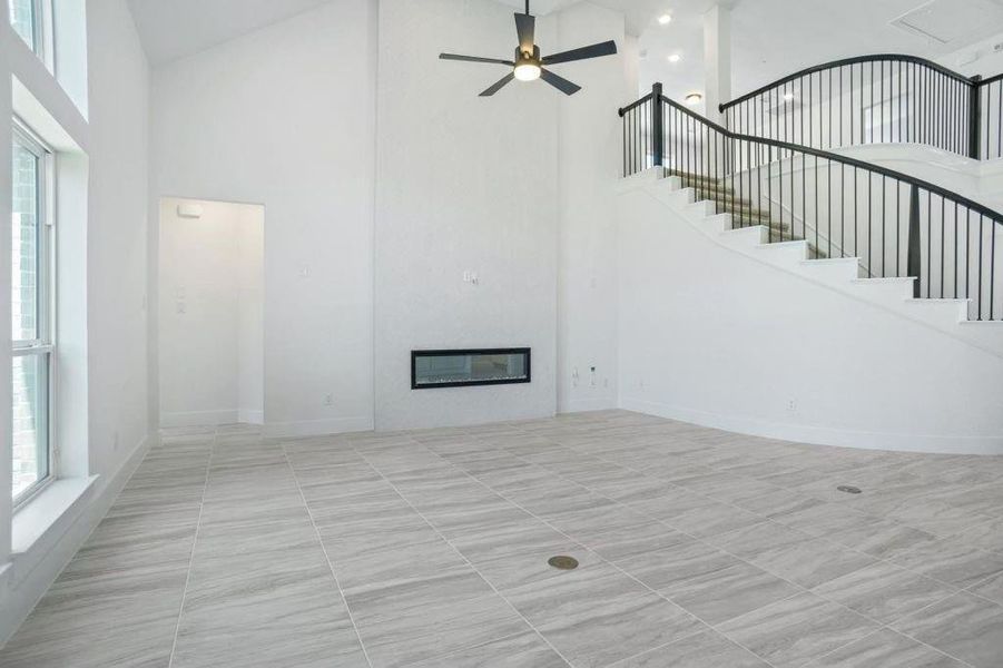 Unfurnished living room with a towering ceiling and ceiling fan