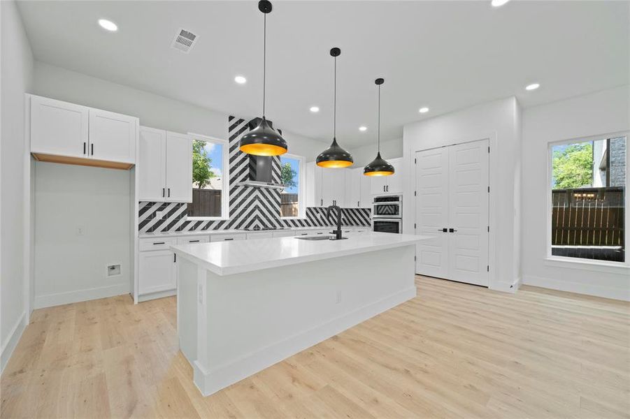 Kitchen featuring tasteful backsplash, white cabinets, stainless steel double oven, light wood-style flooring, and recessed lighting