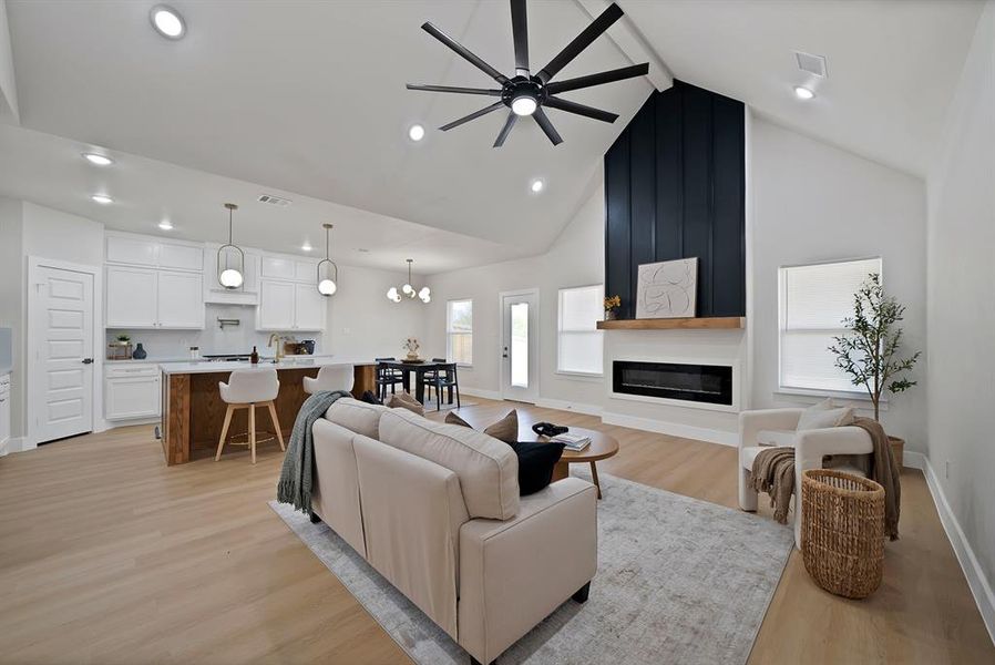 Living area with light wood-style floors, high vaulted ceiling, ceiling fan, beamed ceiling, and a chandelier Living area with light wood-style floors, high vaulted ceiling, ceiling fan, beamed ceiling, and a chandelier