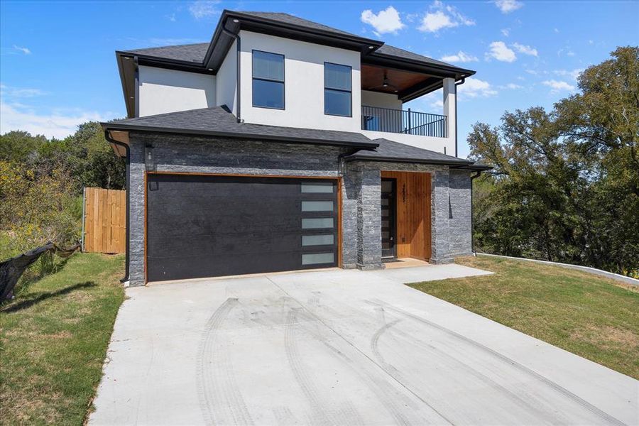 Modern home with a garage, a balcony, and a front lawn