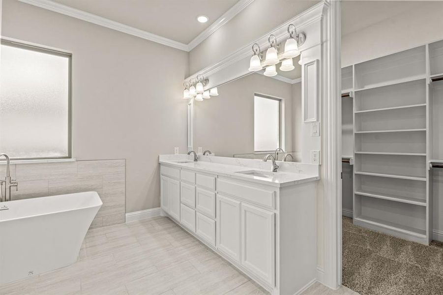 Full bathroom featuring double vanity, crown molding, a soaking tub, a walk in closet, and recessed lighting Full bathroom featuring double vanity, crown molding, a soaking tub, a walk in closet, and recessed lighting